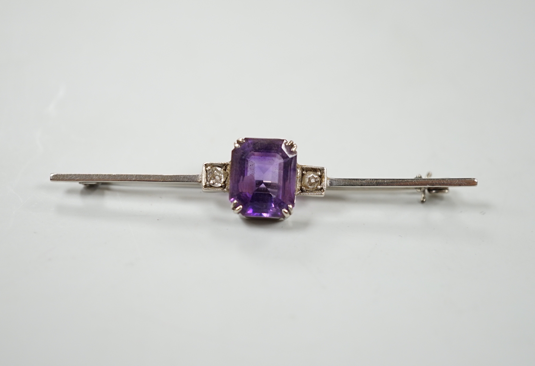 A 9ct white metal, amethyst and diamond set three stone bar brooch, 56mm, gross weight 3.7 grams, with original 1950's receipt.